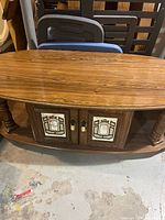 Top and front view of the oval coffee table showing mirrored cabinet doors, turned legs and lower shelf