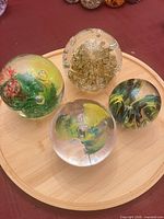 Top view of four glass paperweights on bamboo tray