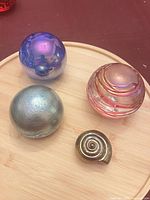 Four glass paperweights on wooden board