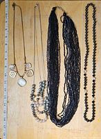Top-down view of all four necklaces laid flat beside ruler