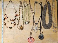 All eight necklaces and pendants laid out with ruler for scale