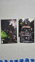 Two comic books laying flat on a light surface showing front covers: Batman/Spawn #1 with Spawn character, and Batman White Knight with urban crime scene.