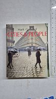 Front cover of the paperback book 'Cities & People' by Mark Girouard, showing an illustration of a European city street scene with people carrying umbrellas.
