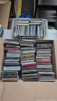 Large collection of music CDs arranged in bins and boxes showing a variety of album covers and spines.