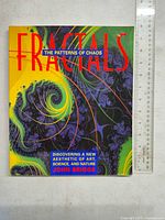Front cover of the softcover book showing fractal artwork in green, yellow, and purple hues with title text in bold red letters.