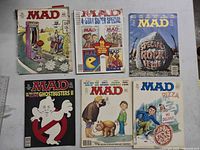 Six MAD Magazine issues arranged on a flat surface showing all covers including Ghostbusters II and pizza delivery parodies.