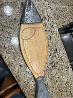 Top view of the fish-shaped wooden cutting board with metal fish head and tail accents, showing recessed groove on cutting surface.