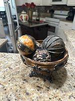 Front angle view of the ceramic centerpiece bowl with three decorative spheres inside on a kitchen countertop.