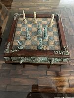 Top-down view of the wooden chess board in play with carved ceramic pieces arranged on squares