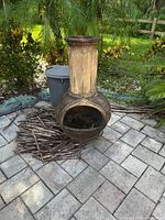 Full view of the clay chiminea showing wide open mouth and tall chimney with decorative vertical ridges.