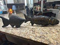 Pair of metal fish sculptures on kitchen counter showing front and side angles