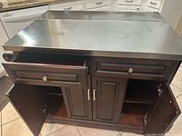Kitchen island with two drawers open and cabinet doors open, showing inside shelves. Stainless steel top visible on island.