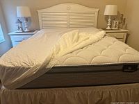 Queen bed frame with new Serta Perfect Sleeper pillow top mattress and two white table lamps on nightstands
