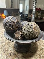 Top view of centerpiece bowl filled with four carved wooden spheres showing ornate floral and scroll raised patterns.