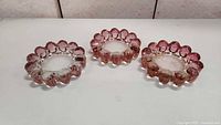 Three bubble glass dishes placed side by side showing two pink and one clear dish, flat on a white surface.