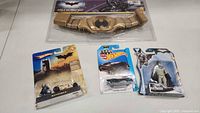 Photo showing the four items including Batman Batmobile, Batman figure, Hot Wheels car, and Child Batman Belt in packaging