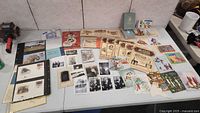 Table display of the entire lot including photos, books, cards, and stamps arranged flat on the table.