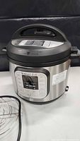 Instant Pot electric pressure cooker showing digital display, stainless steel body, and handle on lid