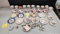 Overview of lot: assorted teacups and saucers with various floral patterns and colors, some with gold trim.