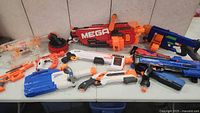 Wide view of all Nerf blasters included in the lot arranged on a table showing various models and sizes