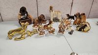 Overview of all 12 collectible dog figurines of various breeds and materials arranged on a flat surface.
