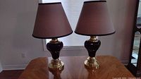 Pair of black and gold table lamps side by side showing brown fabric shades and gold bases