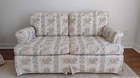 Front view of floral pattern loveseat showing two seat and two back cushions, rolled arms, and fabric upholstery with vertical floral stripes pattern.