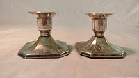 Front angled view showing the two matching silver plated candle holders with hexagonal bases and signs of tarnish.