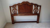 Front view of wooden queen size headboard showing design and condition.