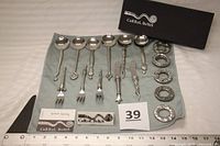 Full set of 16 Carrol Boyes flatware pieces on cloth with brand boxes visible