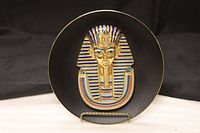 Front view of black porcelain plate with raised Tutankhamun mask design