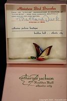 box lid showing branding and ID card with brooch inside