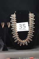 Full view of necklace and earrings on display stand