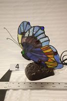 Left side view showing stained glass wings, cabochon accents, metal base, scale ruler