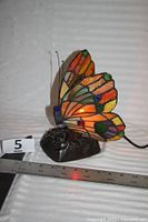 Left side view of stained-glass butterfly lamp with ruler for scale