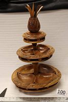Full view of three-tier carved wooden lazy Susan with pineapple top and removable bowls