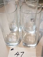 Four clear square highball glasses grouped; height and shape visible