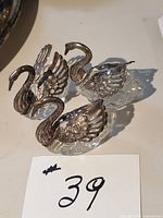 Three silver plate and crystal swan salt cellars grouped on tabletop