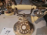 Oblique view showing full telephone with handset, base, brass-tone finish and rotary dial