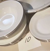 stack of dinner plates, soup bowls, bread & butter plates showing silver rim