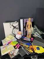 All items on table: notebooks, sticky notes, writing instruments, tools, mannequin