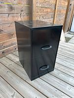 Closed view of black two-drawer metal file cabinet on wooden deck