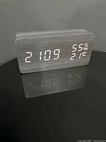 Front view of digital alarm clock displaying time, humidity and temperature