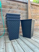 Four stacked black rattan-style planters on deck