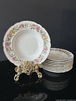 Stack of nine floral gold-rimmed rim soup bowls with one displayed upright