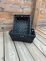 Two black wicker baskets stacked on deck