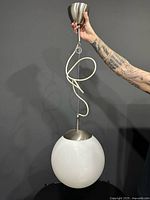 Pendant light held up showing full globe, canopy, cord and suspension cable