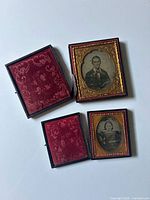 Both ambrotypes open, showing full cases and interior velvet pads