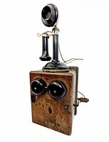 Front view of oak ringer box with attached handset showing bells and crank