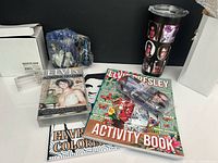 group shot showing mug, tumbler, eyeglass case, VHS, two books, and boxes